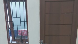 A closed brown door with a metal handle and a window with metal bars.