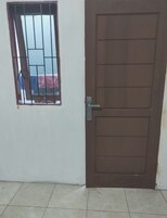 Una puerta marrón cerrada con picaporte de metal y una ventana con barrotes.