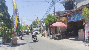 A street with shops, a motorbike, and flags.