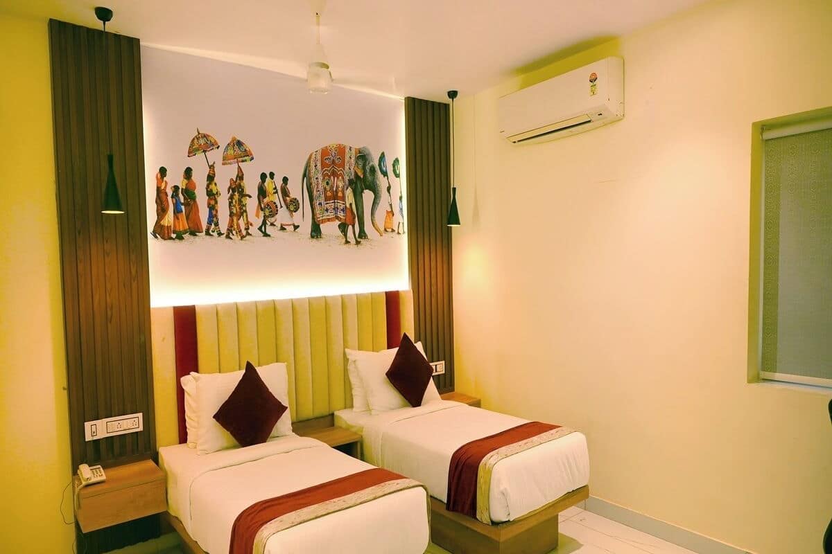 A hotel room with two beds, a wall-mounted air conditioner, and a decorative mural above the beds.