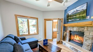 A living room with a stone fireplace, a large window, and a blue wall.