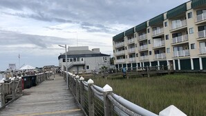 Un muelle de madera que conduce a un edificio con varios balcones y un letrero de marina al fondo.
