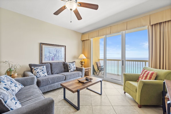 Relax in this spacious living room with a sofa set, armchair, and coffee table, perfect for unwinding with a view of the outdoors.