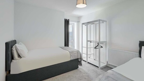 Moderni hotellihuone, jossa on kaksi sänkyä, erillinen vaatehuone ja suuri ikkuna.