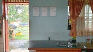 A room with a desk, a window with curtains, and three papers on the wall.