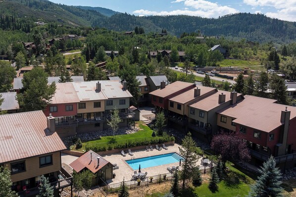 A residential area with houses, a swimming pool, and a mountainous backdrop.