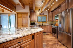 A kitchen with wooden cabinets, a stainless steel refrigerator, and a granite countertop.