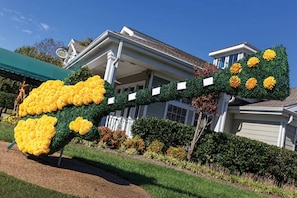 Uma casa com jardim e um grande arranjo floral artificial.