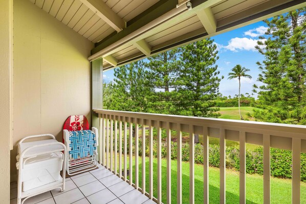 A balcony with a view of a well-manicured lawn and trees.