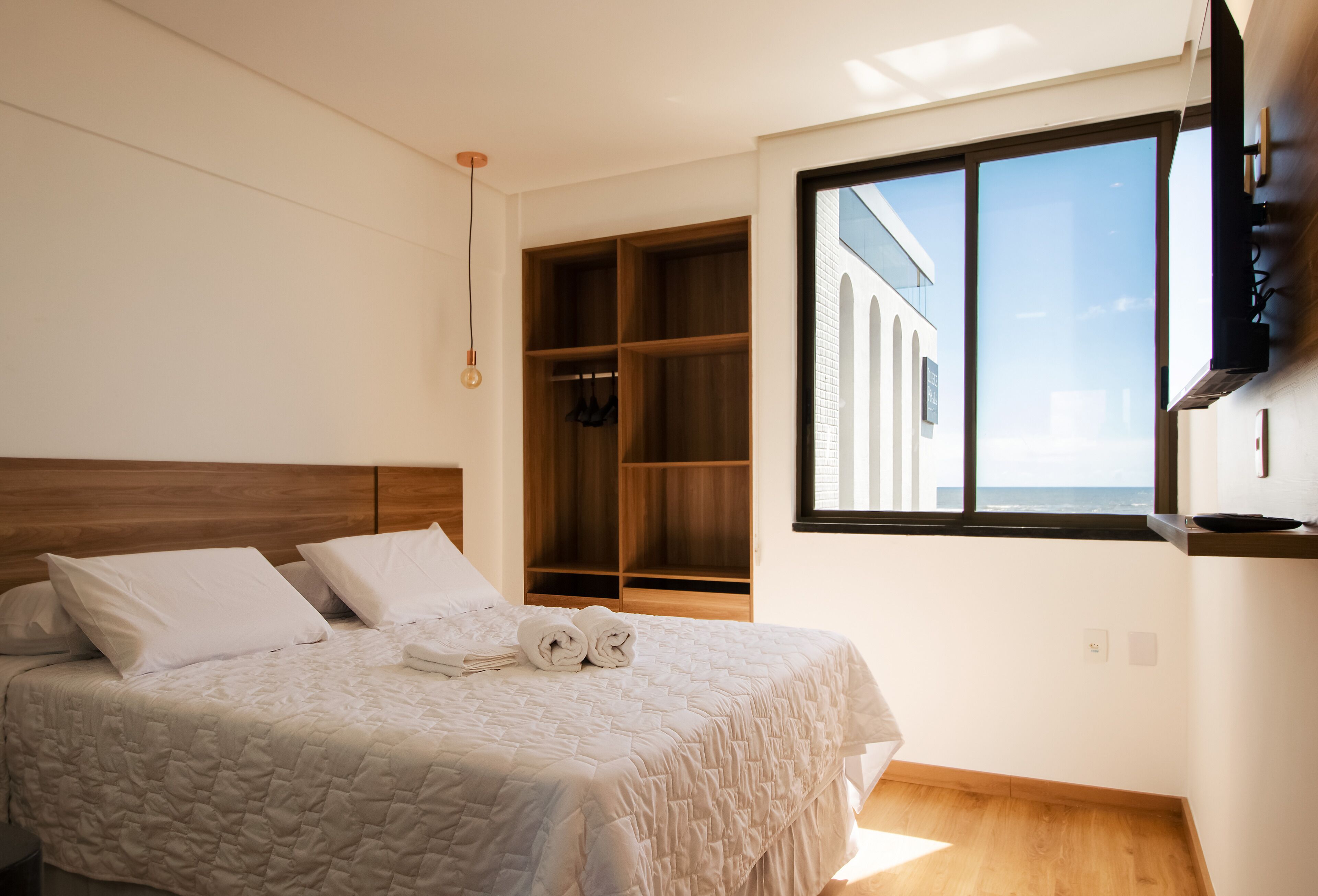 Un dormitorio con cama, armario de madera y ventana grande con vistas.