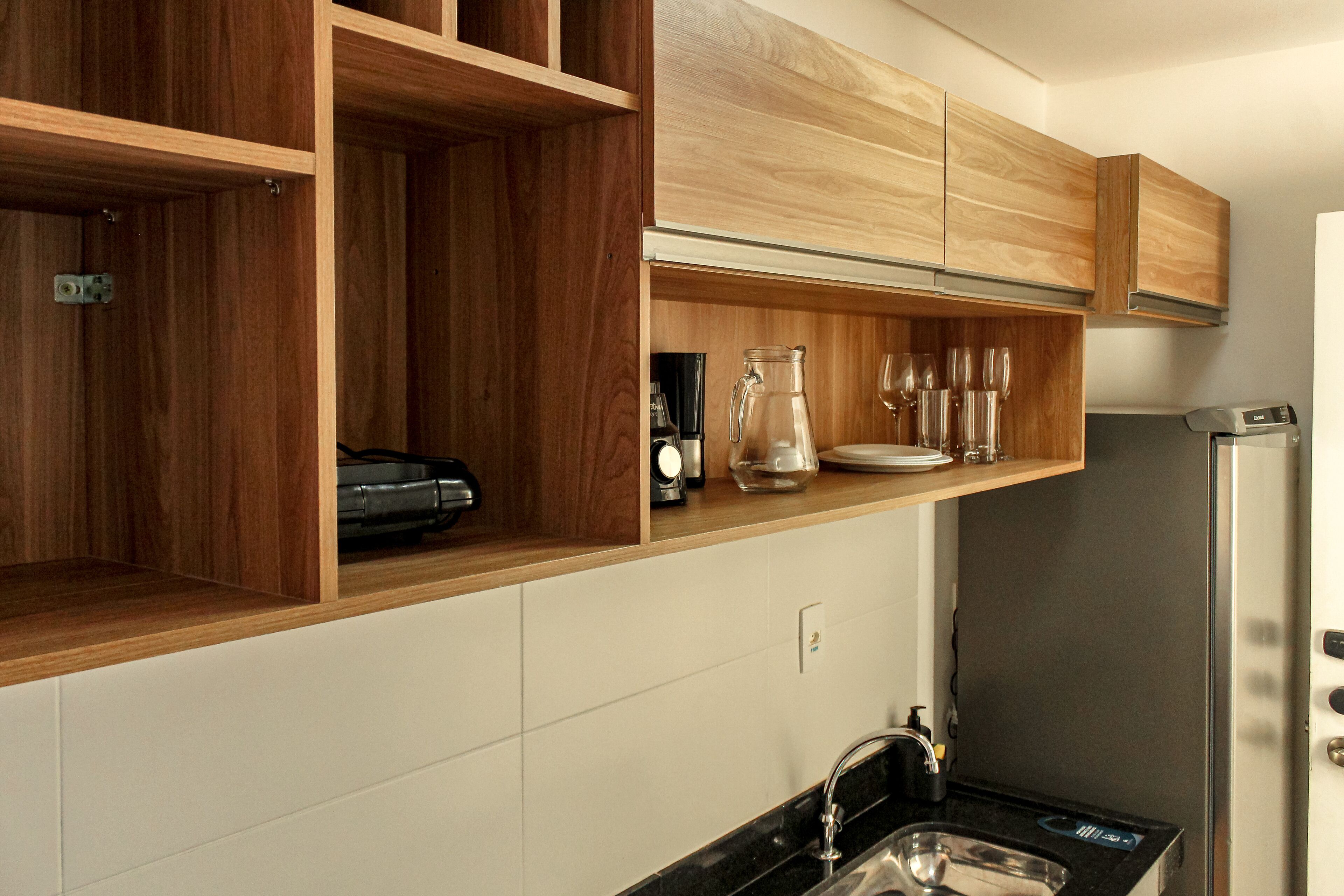 A kitchen with wooden cabinets, a stainless steel refrigerator, and a black countertop.