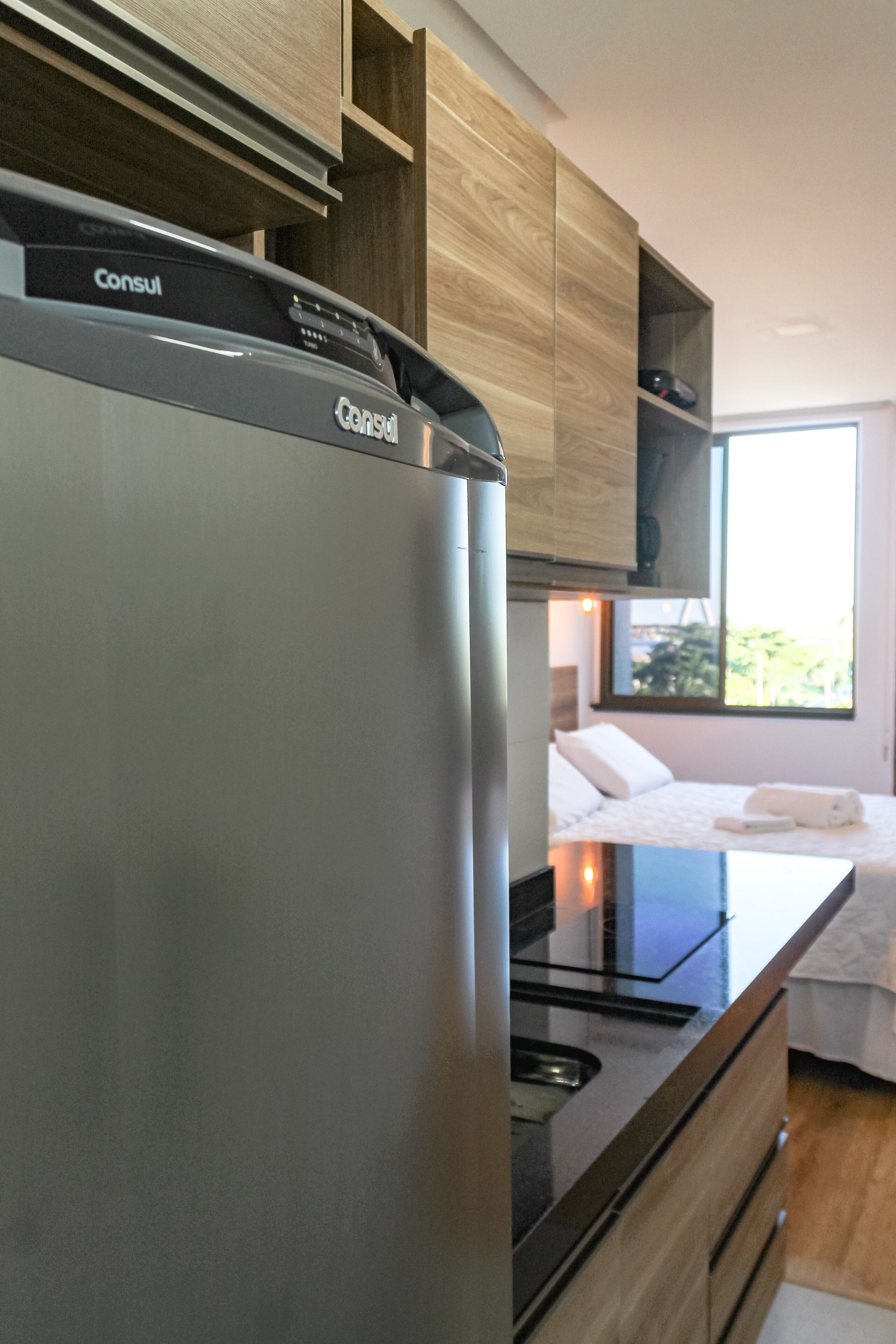 Une cuisine moderne dotée d’un réfrigérateur en acier inoxydable, de meubles en bois et d’une cuisinière encastrée.