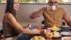 Una mesa de comedor con platos de comida, un vaso de jugo de naranja y una taza.