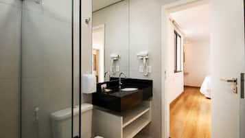 Une salle de bain moderne avec un lavabo noir, des toilettes blanches et une douche à l’italienne en verre.