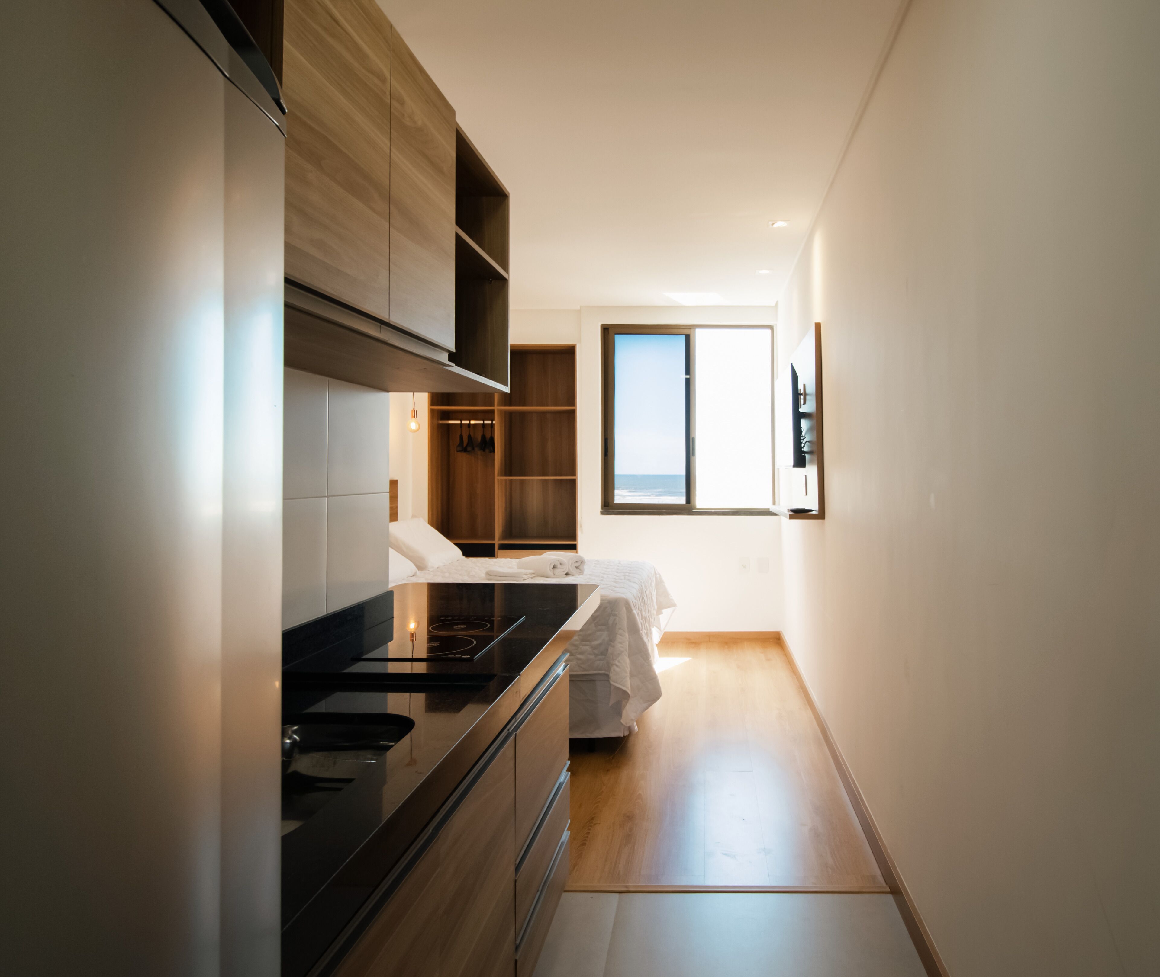 Cocina moderna con estufa integrada, armarios de madera y vistas al océano a través de una ventana.
