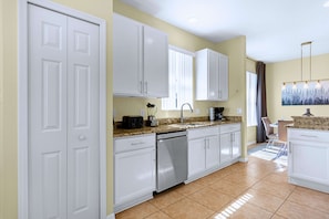 A modern kitchen with white cabinets, a dishwasher, a toaster, and a coffee maker. - Upstay: Crystal Cove Resort Villa w/ Pool & Games (Kissimmee)