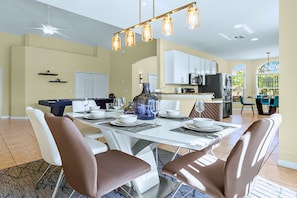 A modern dining area with a white table set for four, surrounded by brown chairs. - Upstay: Crystal Cove Resort Villa w/ Pool & Games (Kissimmee)