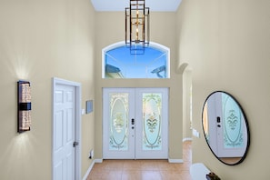 A hallway with a white door, a wall-mounted light fixture, and a large mirror. - Upstay: Crystal Cove Resort Villa w/ Pool & Games (Kissimmee)