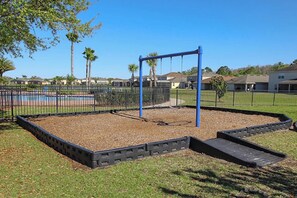 A playground with a swing set, a small pool, and a fenced area with grass and trees. - Upstay: Crystal Cove Resort Villa w/ Pool & Games (Kissimmee)