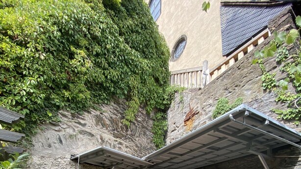 En mysig utomhusplats med sittplatser, en stenmur som bakgrund, en Buddha-staty och en pergola.