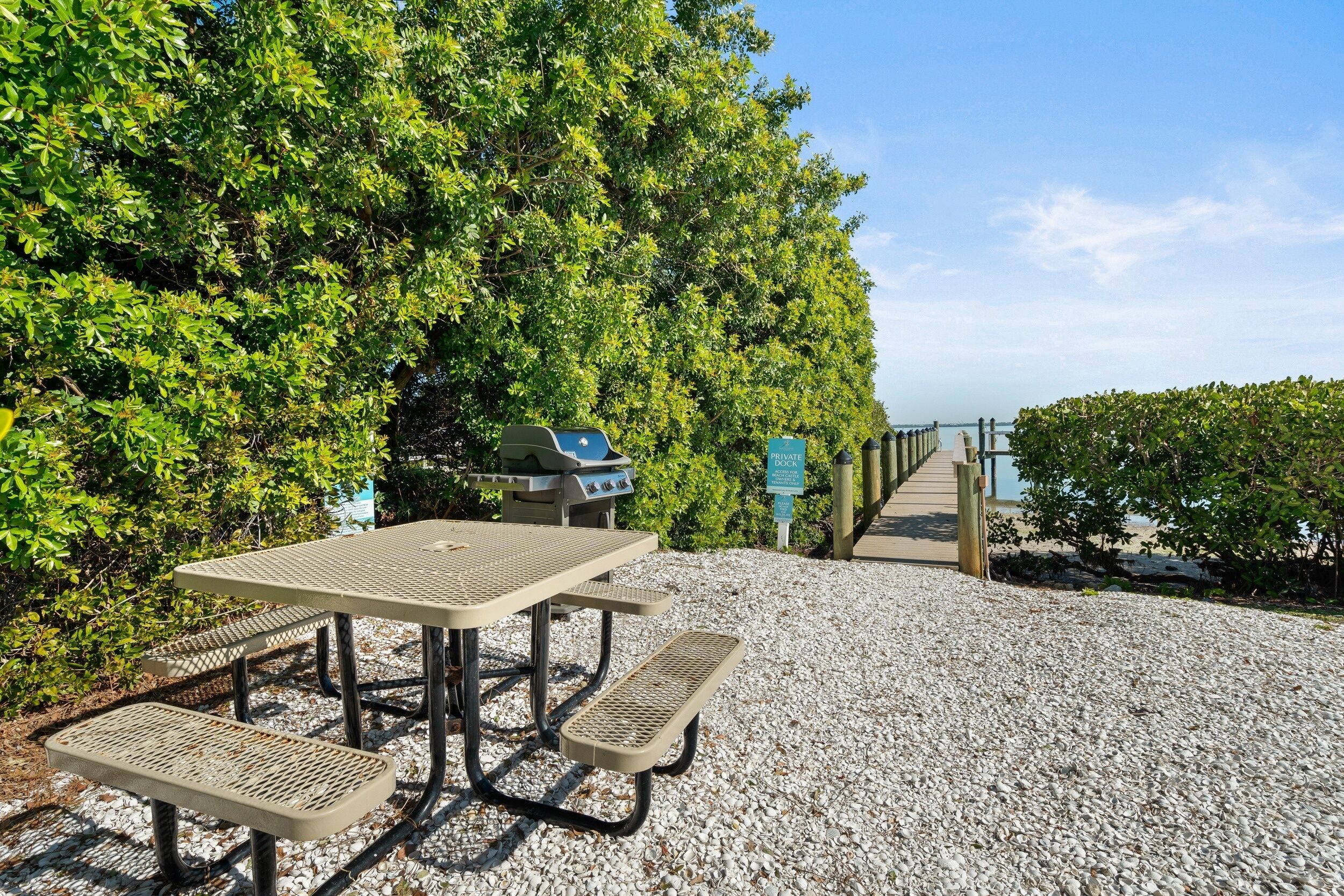 Une table de pique-nique avec des bancs, un barbecue et un panneau indiquant qu’il s’agit d’un quai privé.