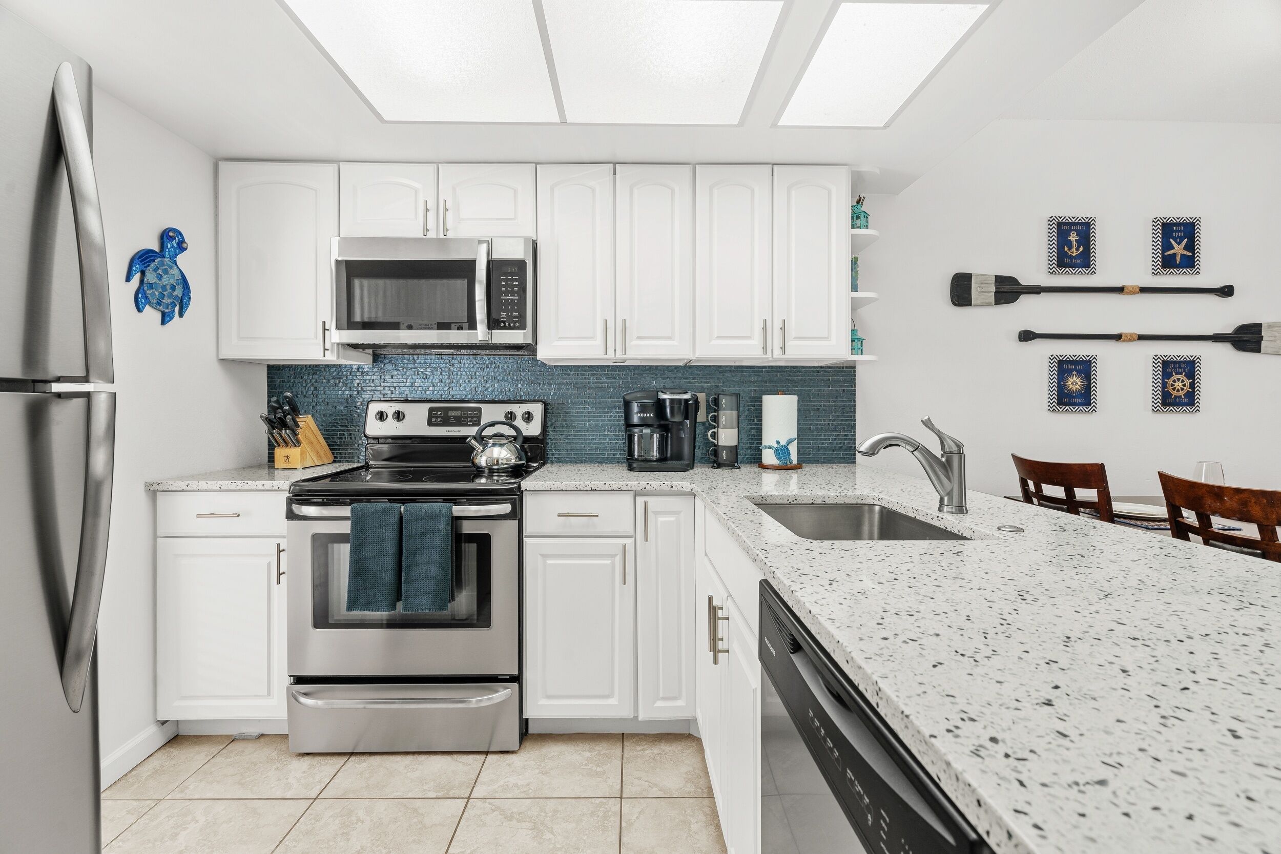 A modern kitchen with white cabinets, stainless steel appliances, and a large island with a sink.