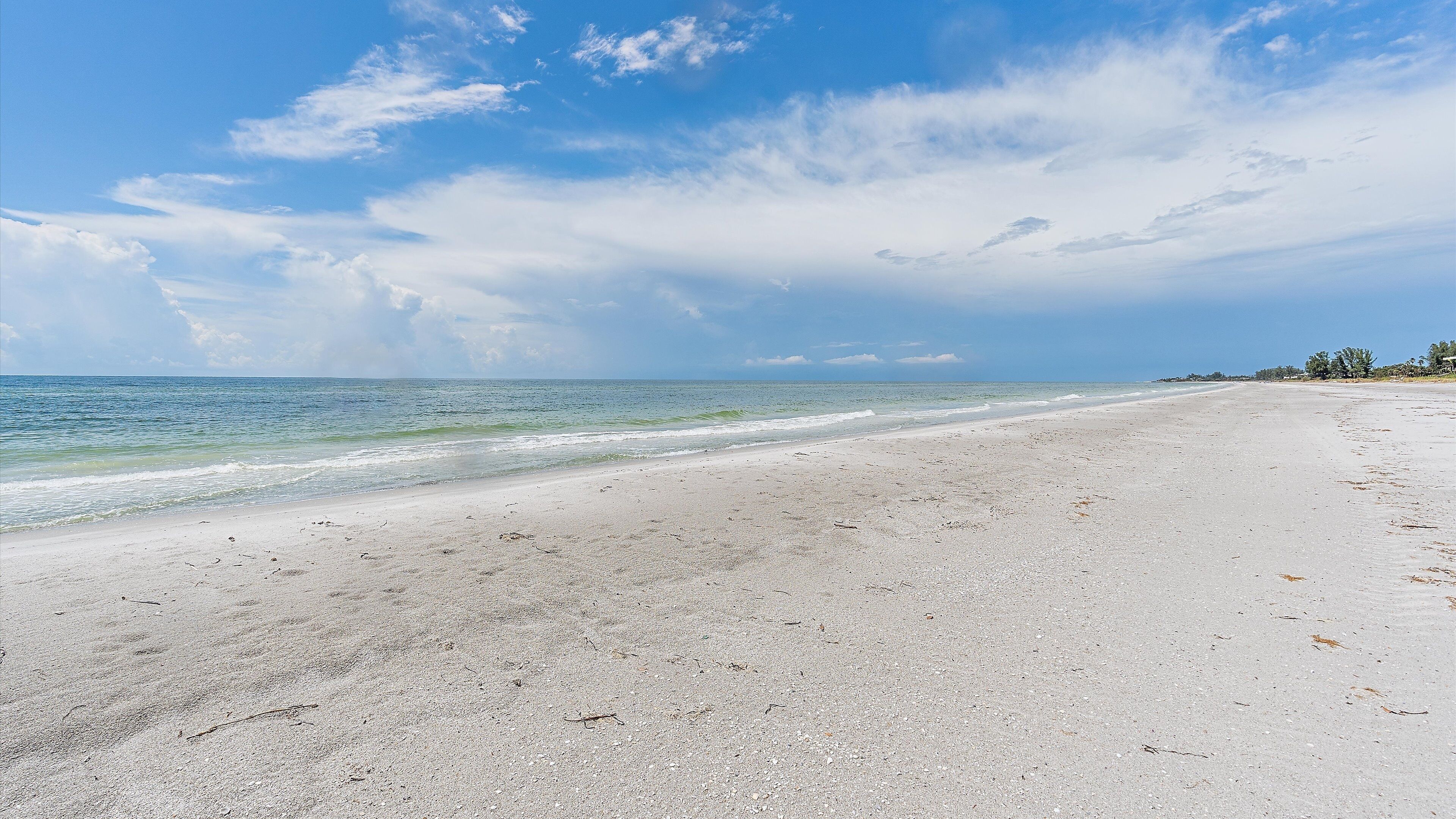 A beach with a wide sandy shore and gentle waves.