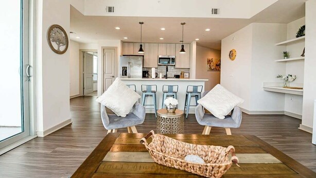 Un espacio habitable moderno con una cocina al fondo, una mesa de comedor con sillas y un ventanal grande.