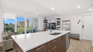 Una cocina moderna con una isla grande, electrodomésticos integrados y vistas al exterior.