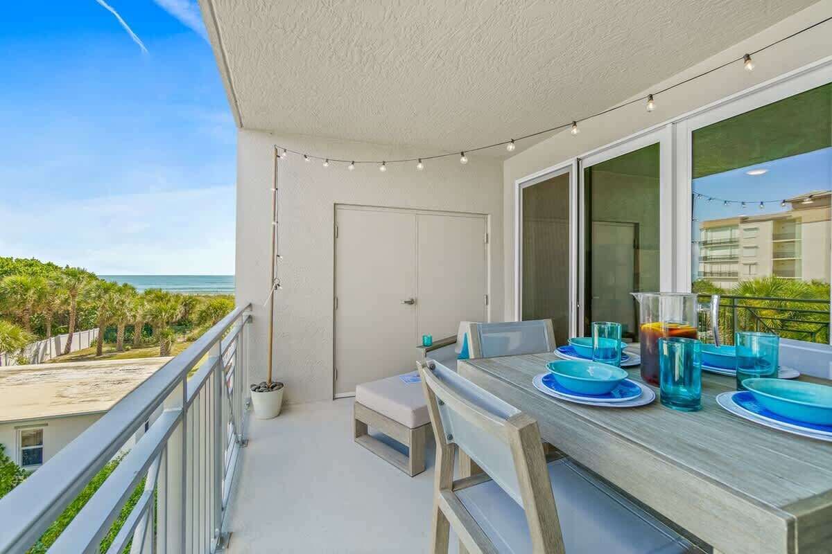 Ein Balkon mit Esstisch, gedeckt für vier Personen, mit Blick auf Strand und Meer.