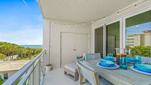 Balcón con mesa para cuatro, con vista a la playa y al océano.