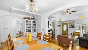 A spacious living room with a wooden dining table, a brown sofa, and a ceiling fan. - Main Level Haven | Steps from the Hot springs | Sleeps 9 (Ouray)