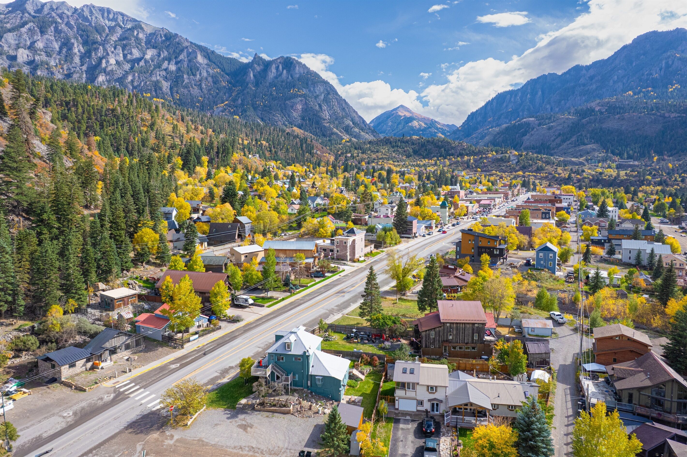 Une ville avec une rue principale, des bâtiments et des montagnes en arrière-plan.