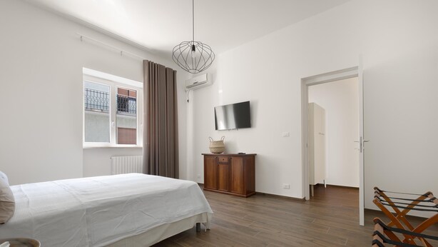 A bedroom with a bed, a wooden cabinet, a television, and a window with curtains. - 3624 Casa di Rosa - Ionio by Barbarhouse (Maglie)