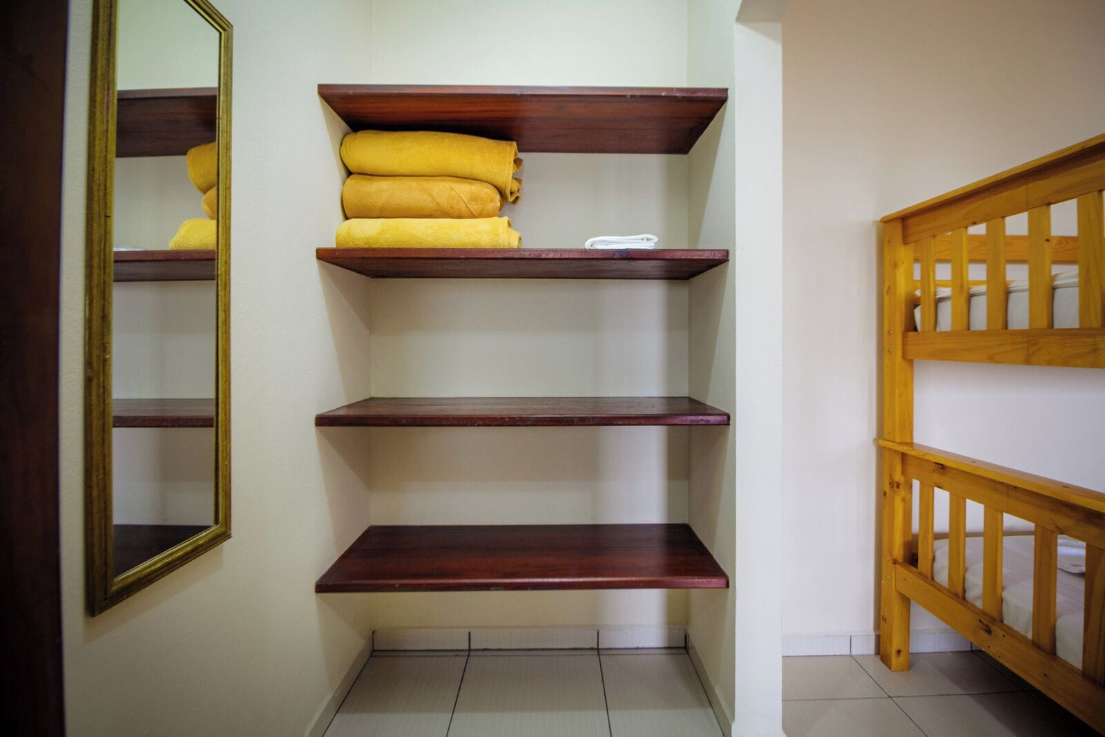 Un couloir avec des étagères en bois, un miroir et une rambarde en bois.
