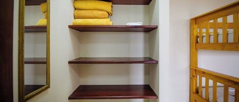 A hallway with wooden shelves, a mirror, and a wooden railing.