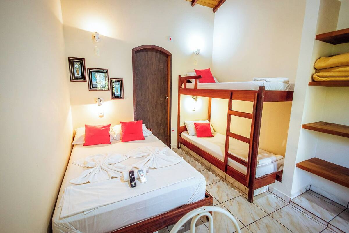 A hotel room with a large bed, a bunk bed, and a wooden wardrobe.