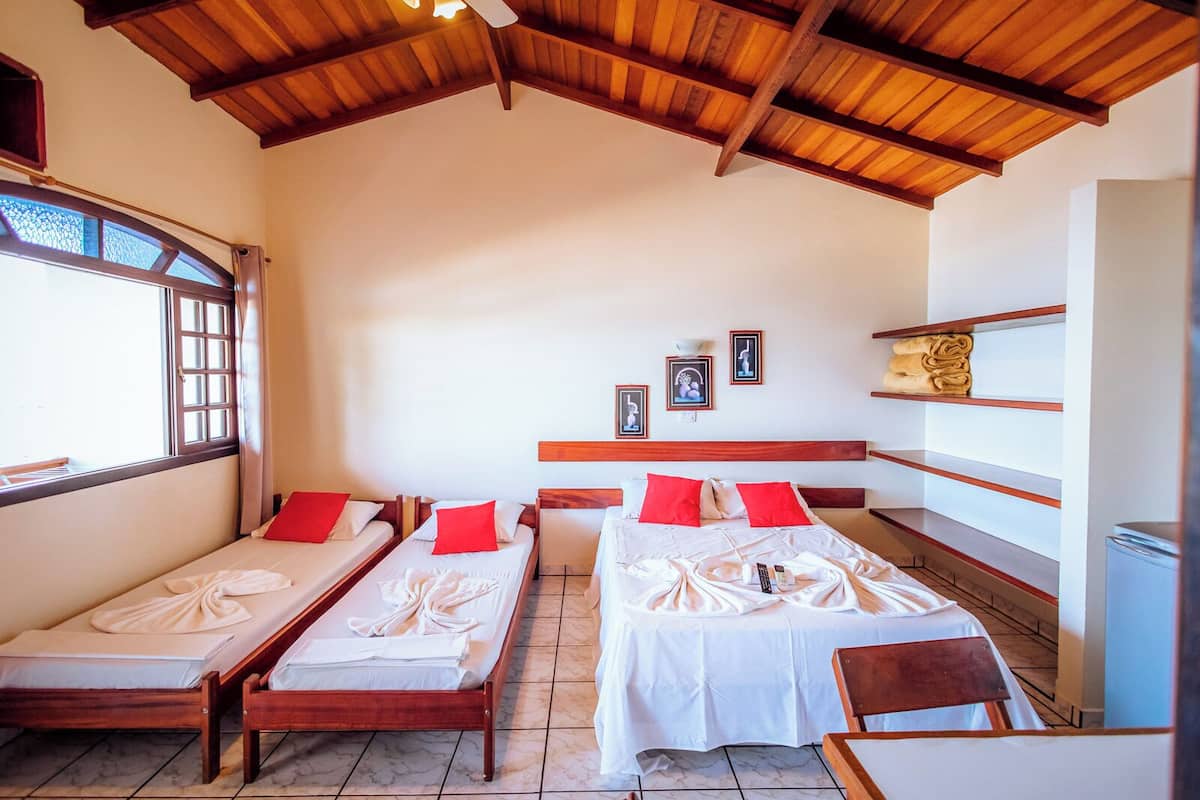 A room with two single beds, a wooden ceiling, a window, and a small table.