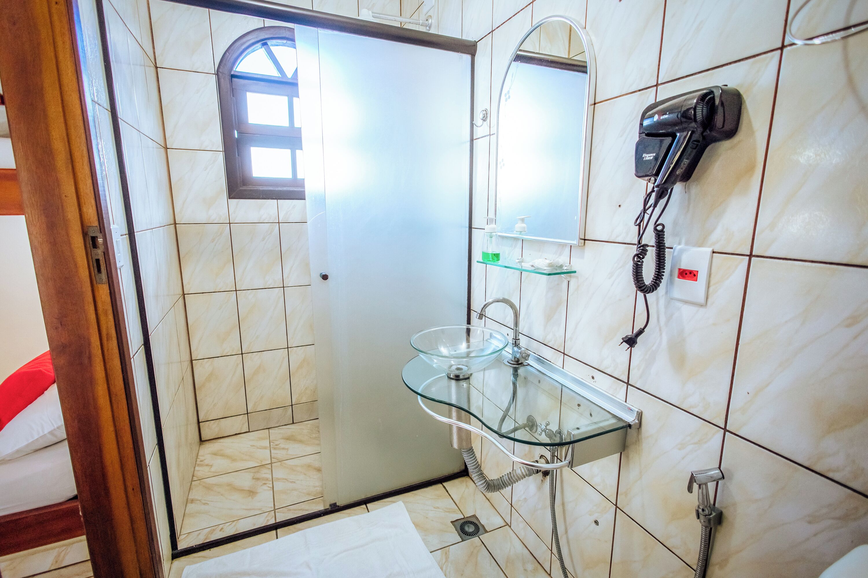 A bathroom with a glass sink, a hairdryer, and a mirror.