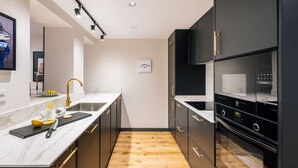 A modern kitchen with black cabinets, a marble countertop, and a wooden floor. - Grand 200m² Luxury Residence, 4 En-Suites, Patio, Gran Vía area Quiet, A/C (Madrid)