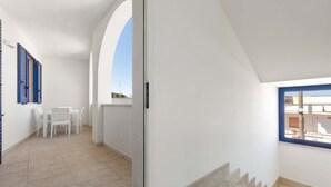 A clean, white interior with a tiled floor, a small seating area, and a window with a view. - 3403 Casa Petrachi - PP by Barbarhouse (Melendugno)