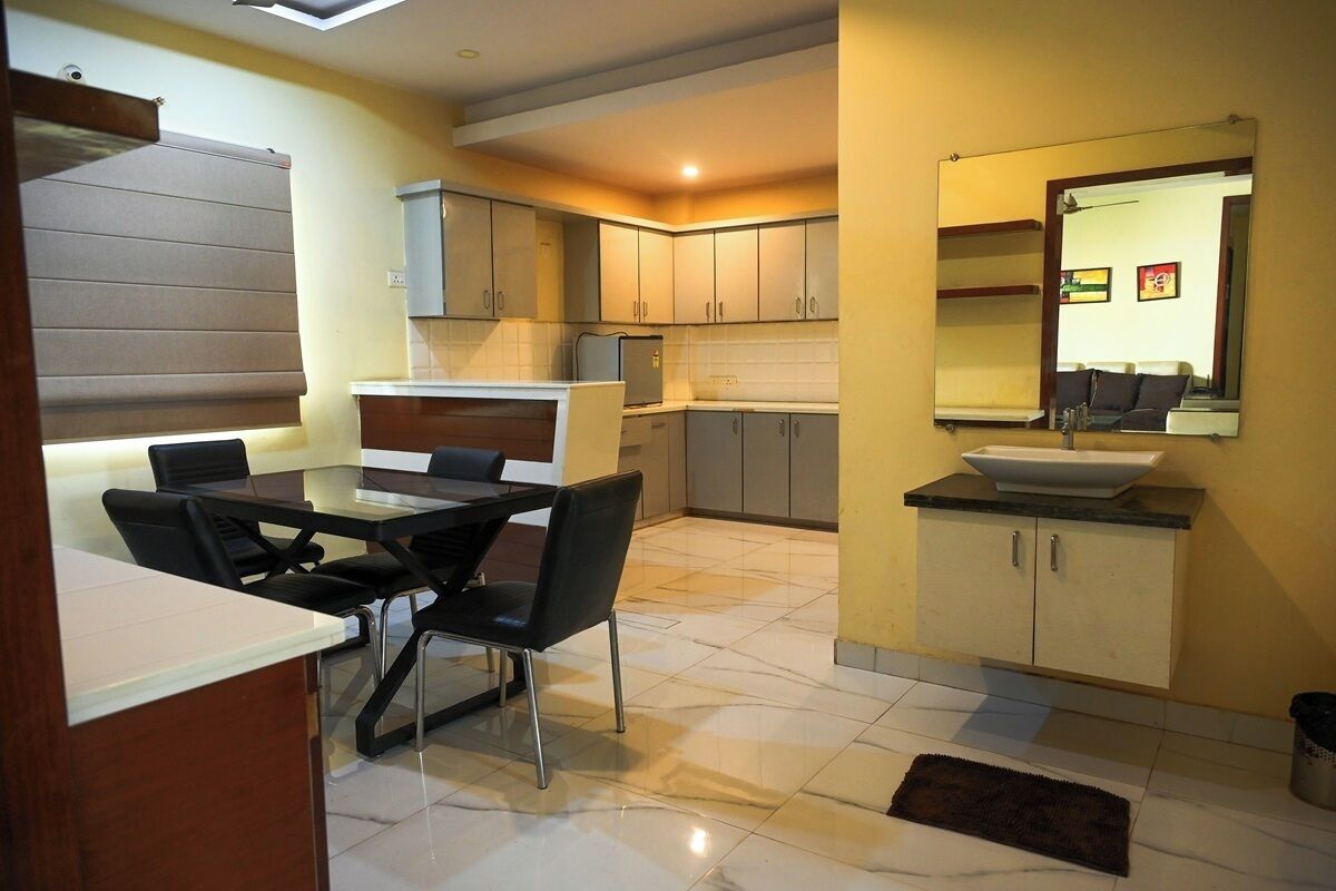 A modern kitchen with a dining area, featuring a large island, cabinets, and a built-in oven.
