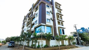 A multi-story residential building with balconies, a car parked in front, and palm trees around. - The Butterfly Luxury Serviced Apartments Ramachandra Vijayawada (Penumuluru)