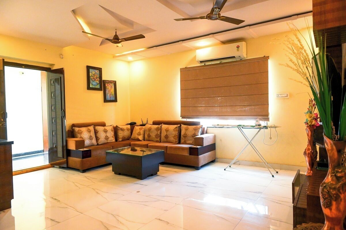 Ein Wohnzimmer mit einem Ecksofa, einem Couchtisch, Deckenventilatoren und einer Klimaanlage.