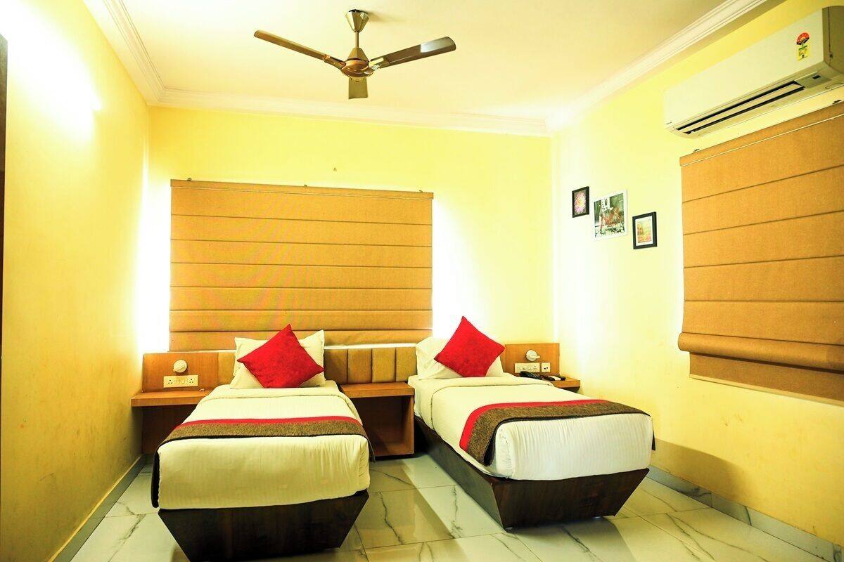 A hotel room with two beds, wooden headboards, a ceiling fan, and an air conditioning unit.