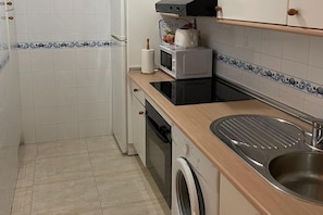 A compact kitchen with a washing machine, a microwave, and a sink.