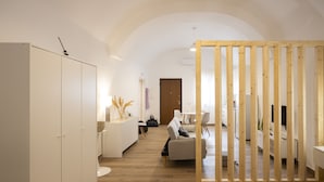 A modern, well-lit room with a wooden wardrobe, a sofa, and a dining area. - Domus 47 Pompei (Pompei)