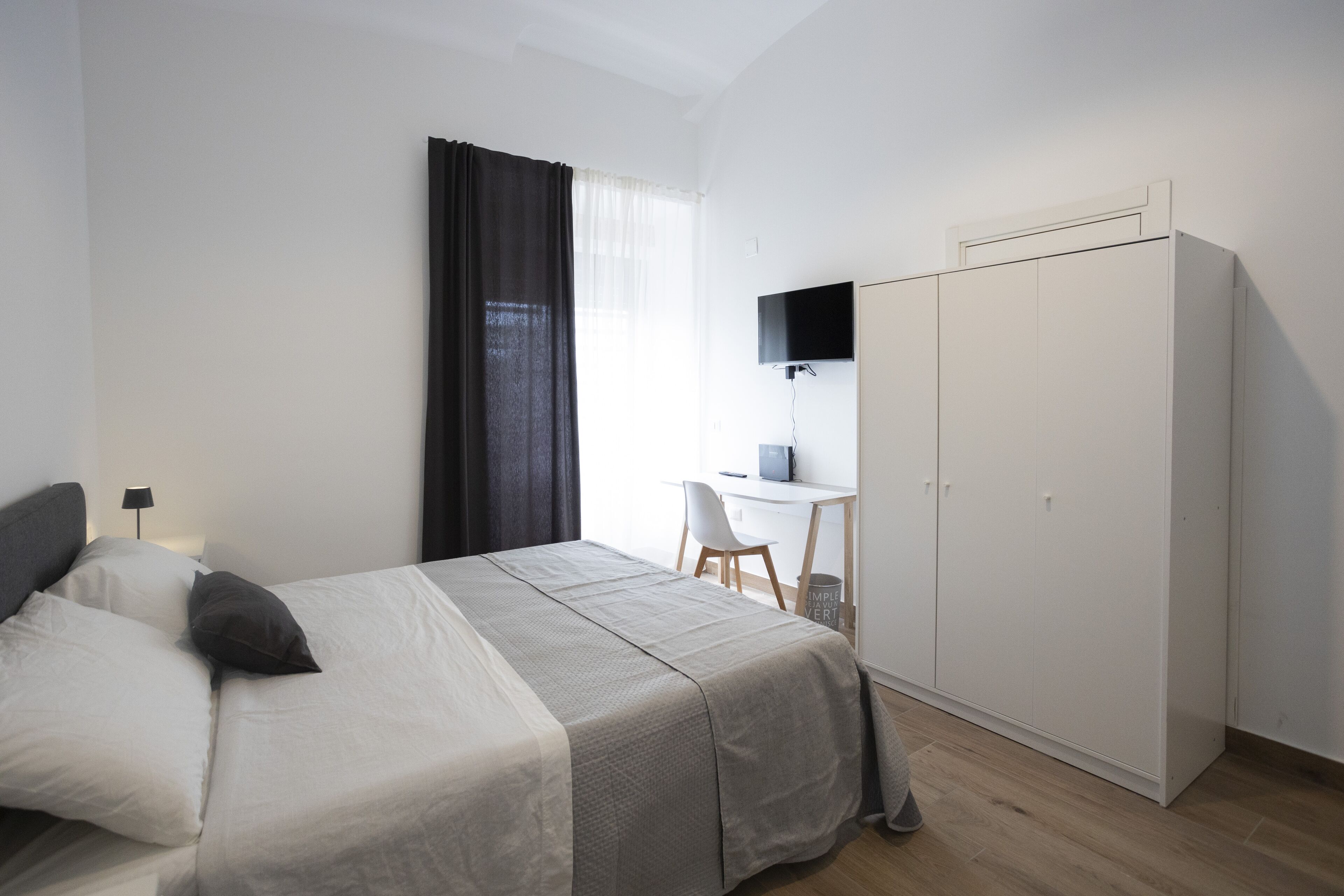 A bedroom with a bed, a desk, and a wardrobe.