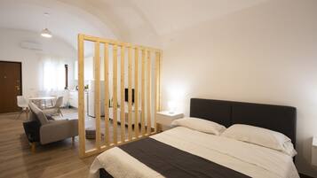 A modern bedroom with a large bed, a wooden partition, a desk, and a chair.