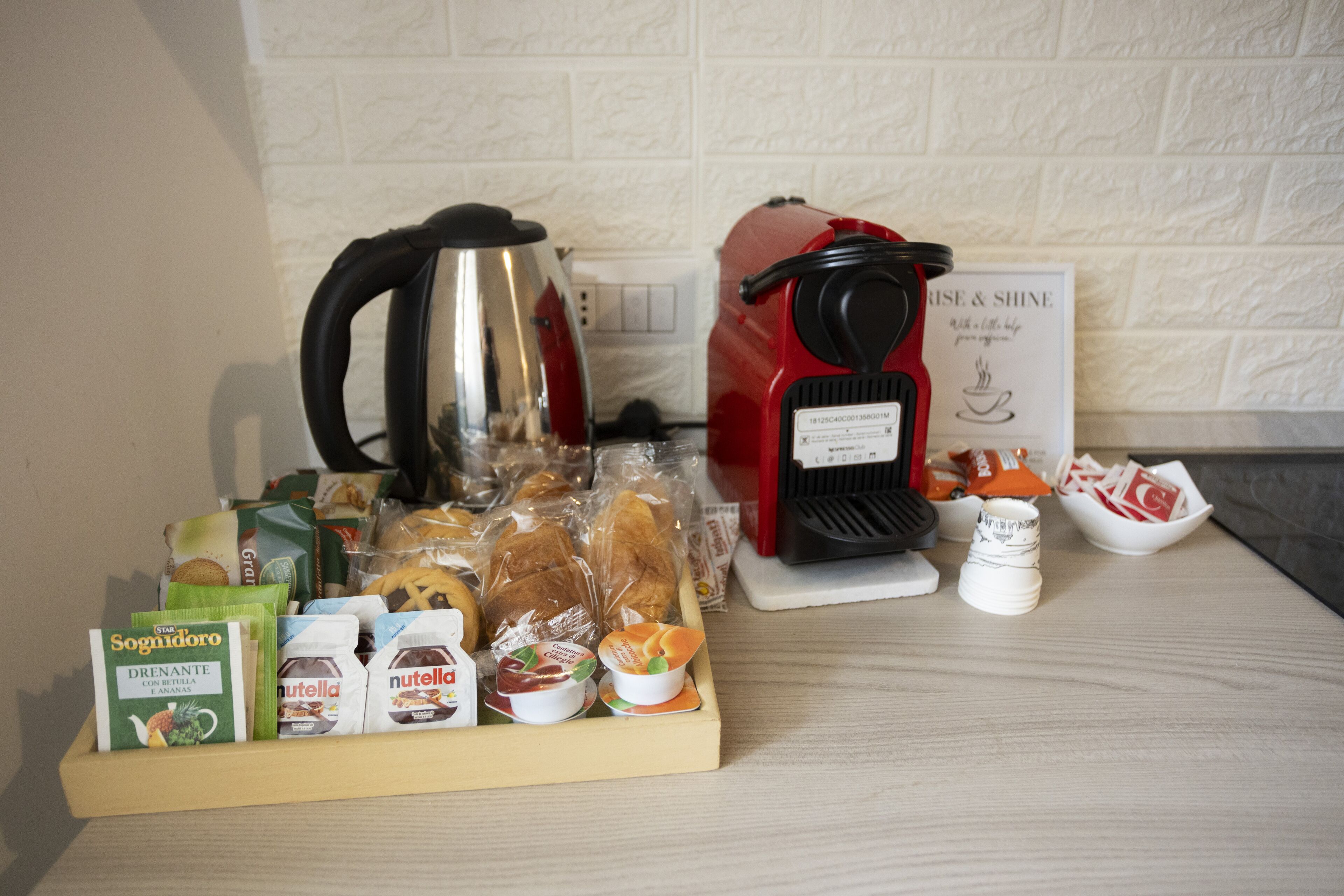 A breakfast buffet with various food items, a coffee maker, and a sign that reads "RISE & SHINE".